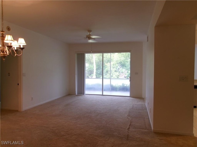 spare room featuring ceiling fan, light carpet, a chandelier, and baseboards