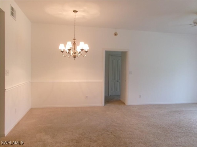 empty room featuring carpet flooring, a chandelier, and baseboards