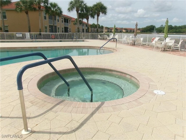 community pool featuring fence, a patio, and a community hot tub