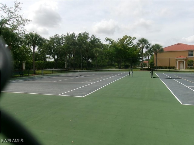 view of tennis court featuring community basketball court and fence