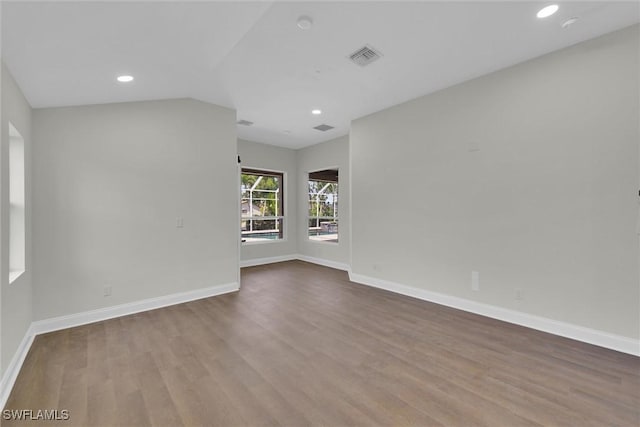 unfurnished room featuring lofted ceiling, baseboards, and wood finished floors