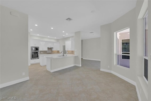 kitchen featuring a sink, a peninsula, visible vents, light countertops, and appliances with stainless steel finishes