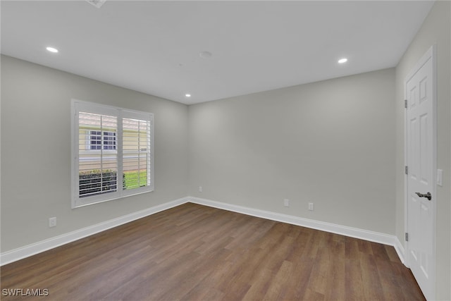 spare room with baseboards, dark wood-style flooring, and recessed lighting