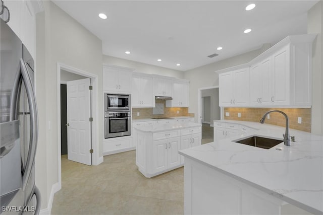 kitchen with under cabinet range hood, white cabinets, appliances with stainless steel finishes, and a sink