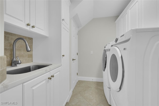 laundry area with baseboards, washing machine and dryer, cabinet space, and a sink