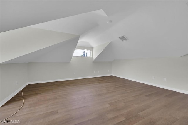 additional living space with wood finished floors, visible vents, baseboards, and lofted ceiling