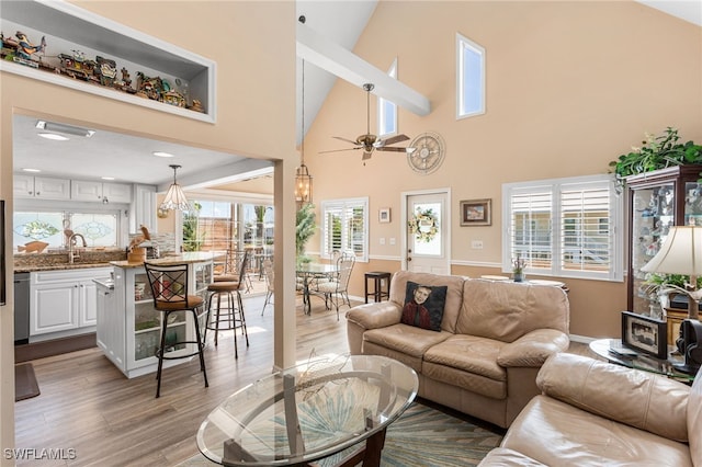 living room with light wood finished floors, a towering ceiling, baseboards, and a ceiling fan