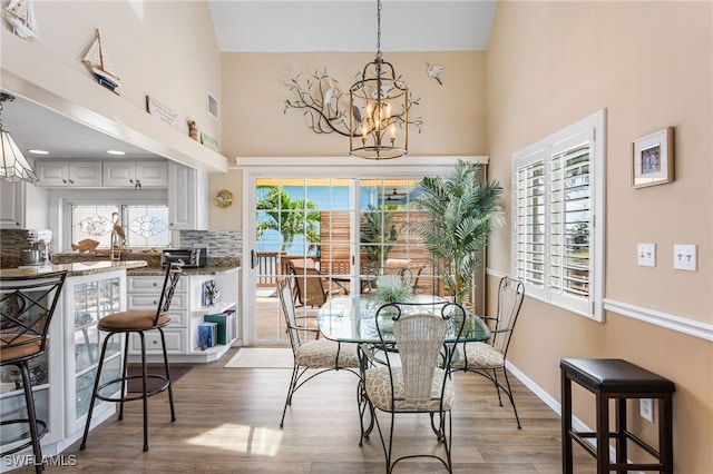dining room featuring an inviting chandelier, light wood-style flooring, high vaulted ceiling, and visible vents
