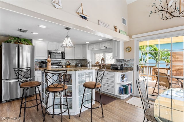 kitchen featuring white cabinets, decorative backsplash, stainless steel appliances, and visible vents