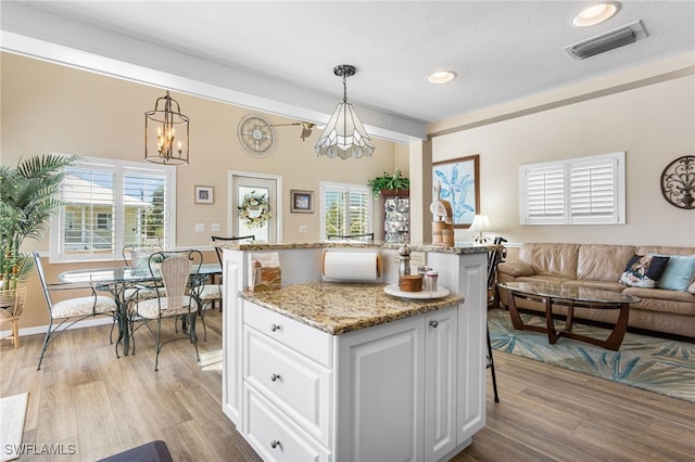 kitchen with white cabinets, visible vents, hanging light fixtures, and open floor plan