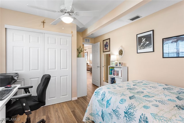 bedroom with a closet, visible vents, wood finished floors, and a ceiling fan