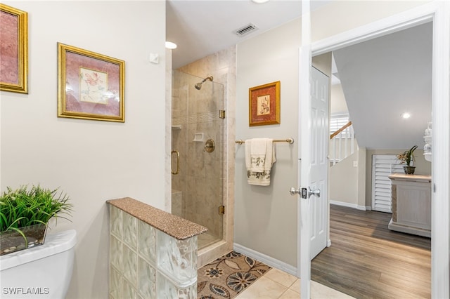bathroom featuring toilet, visible vents, baseboards, and a stall shower