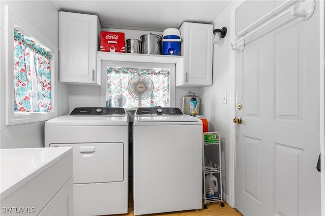 washroom with light wood finished floors, washing machine and dryer, and cabinet space