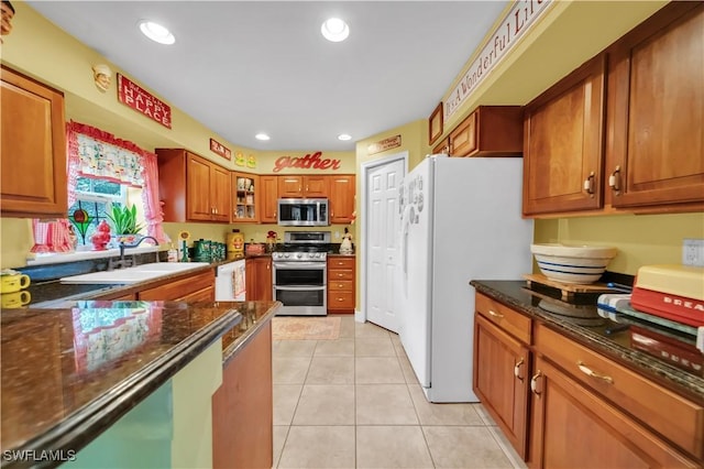 18511 Slater Rd, North Fort Myers, FL 33917 - kitchen featuring appliances with stainless steel finishes, brown cabinetry, a sink, dark stone counters, and light tile patterned floors