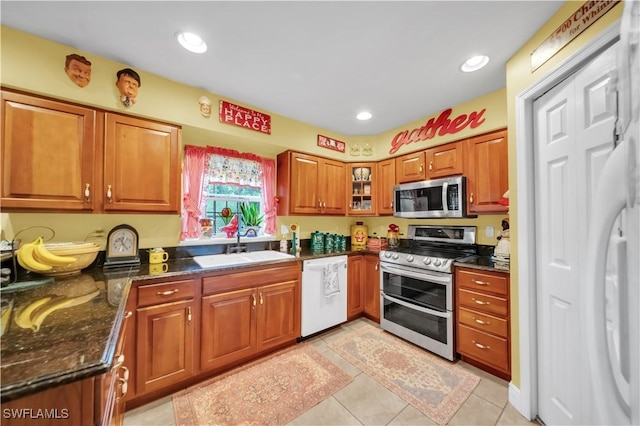 18511 Slater Rd, North Fort Myers, FL 33917 - kitchen featuring stainless steel appliances, brown cabinetry, a sink, dark stone countertops, and light tile patterned flooring