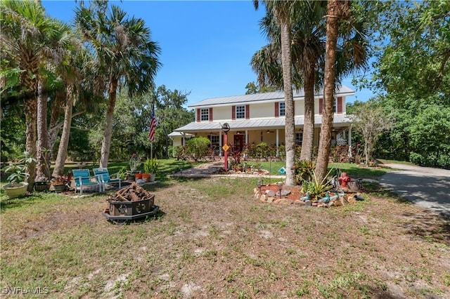 18511 Slater Rd, North Fort Myers, FL 33917 - view of front of property with an outdoor fire pit, covered porch, a front lawn, and metal roof