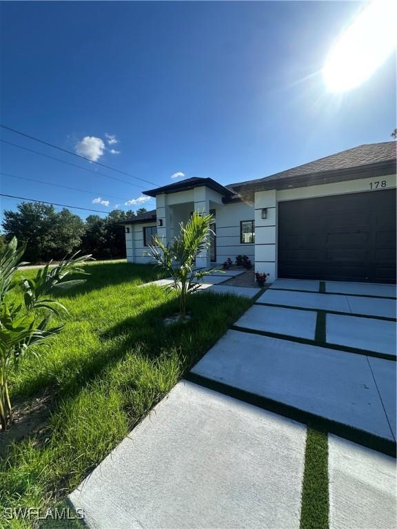 178 Mcarthur Blvd, Lehigh Acres, FL 33974 - view of front facade with a front lawn, driveway, and a garage