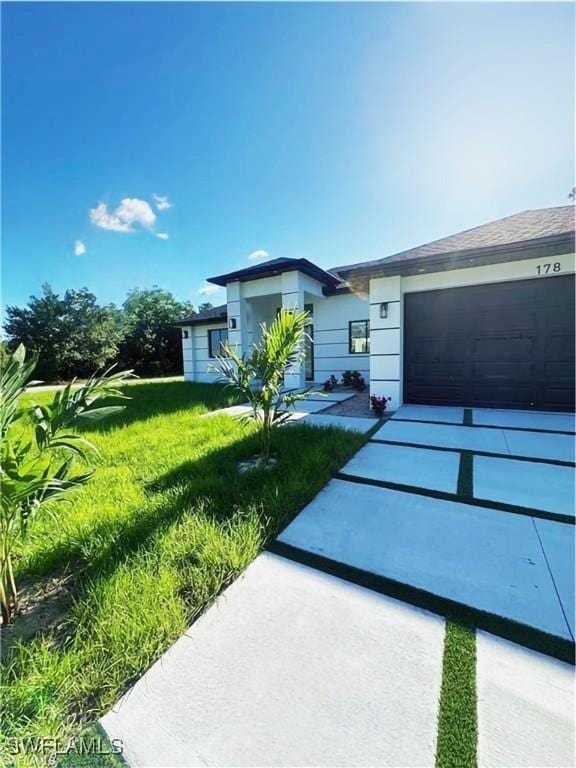 178 Mcarthur Blvd, Lehigh Acres, FL 33974 - view of front of house with a front lawn, driveway, and an attached garage