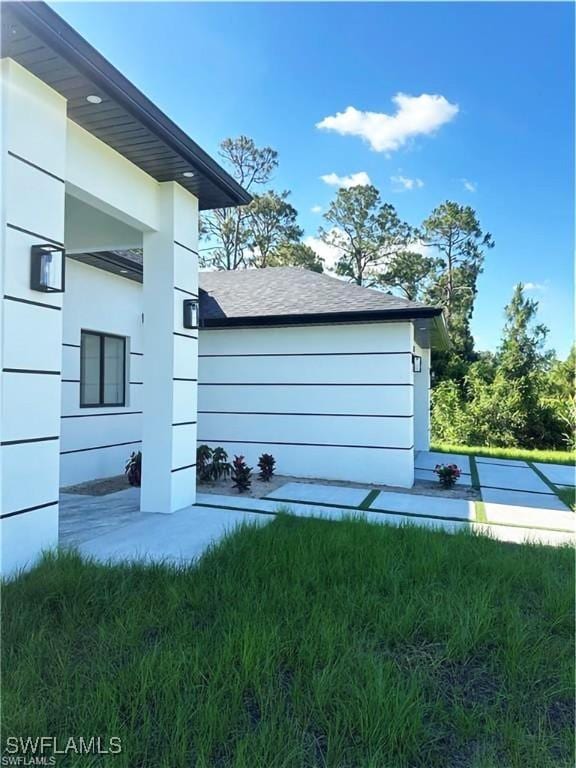 178 Mcarthur Blvd, Lehigh Acres, FL 33974 - view of property exterior featuring roof with shingles and a yard