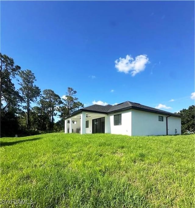 178 Mcarthur Blvd, Lehigh Acres, FL 33974 - back of property with stucco siding and a yard