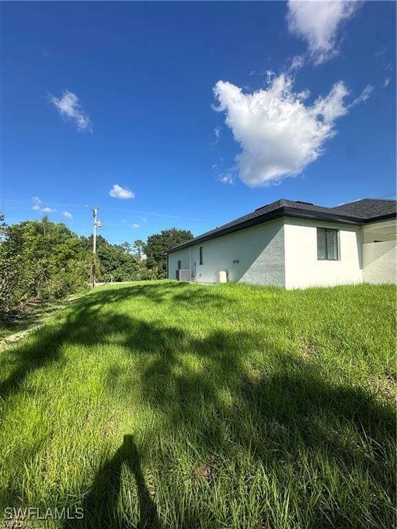 178 Mcarthur Blvd, Lehigh Acres, FL 33974 - view of side of home with stucco siding and a lawn