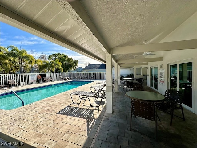 community pool with outdoor dining area, a fenced backyard, and a patio area
