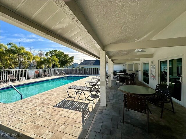 community pool with outdoor dining area, a fenced backyard, and a patio area