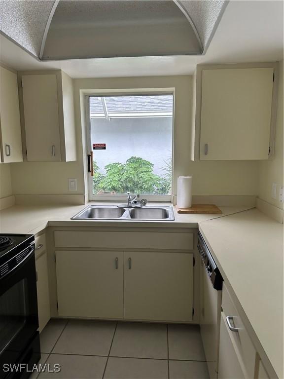 kitchen with a sink, light countertops, electric range, and light tile patterned flooring