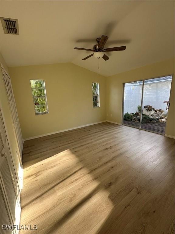 unfurnished room with a ceiling fan, baseboards, wood finished floors, lofted ceiling, and visible vents