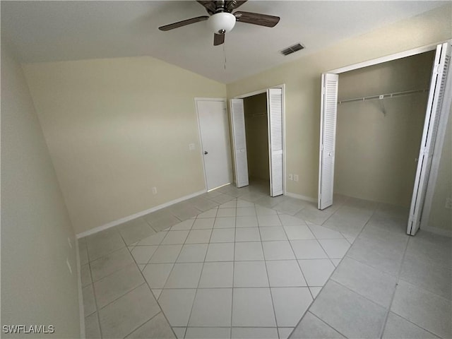 unfurnished bedroom with visible vents, multiple closets, light tile patterned flooring, ceiling fan, and vaulted ceiling