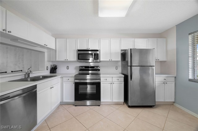 kitchen featuring stainless steel appliances, a sink, white cabinetry, light countertops, and a textured ceiling