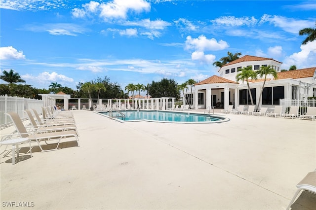 community pool with fence and a patio area