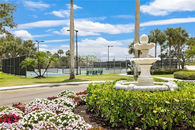 view of community featuring a tennis court and fence