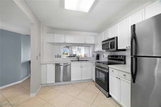 kitchen with appliances with stainless steel finishes, a sink, a textured ceiling, white cabinetry, and light countertops