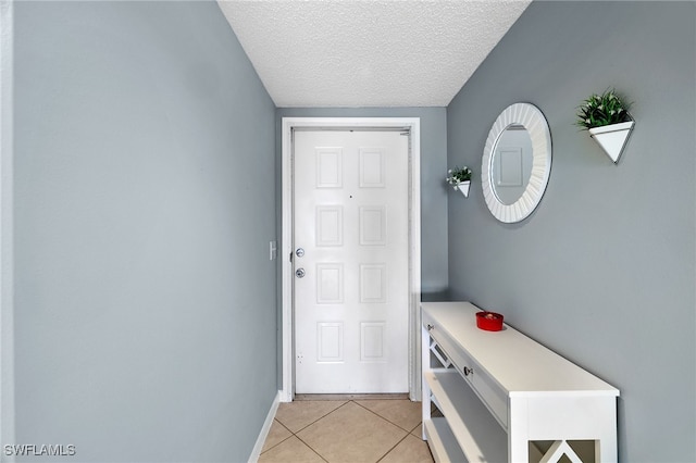 doorway to outside with light tile patterned flooring, a textured ceiling, and baseboards