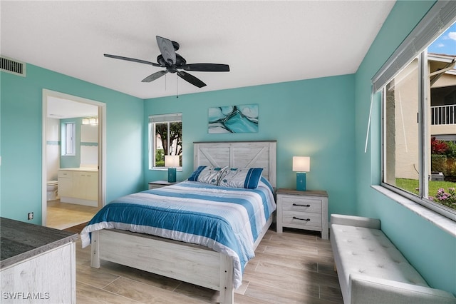 bedroom featuring wood tiled floors, ensuite bath, and a ceiling fan