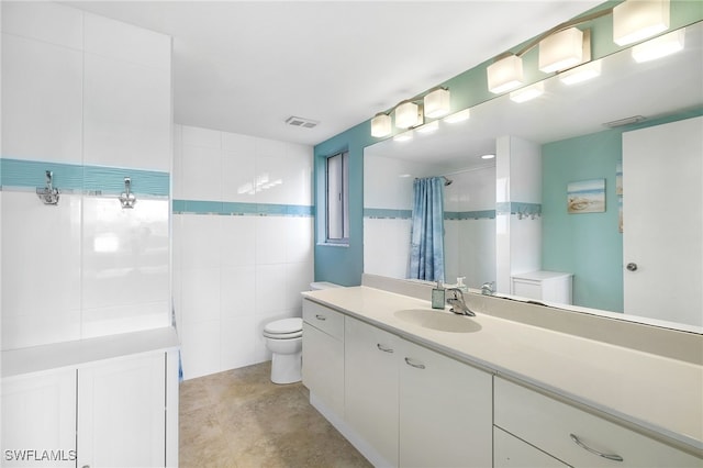 full bathroom featuring toilet, a tile shower, tile walls, and vanity