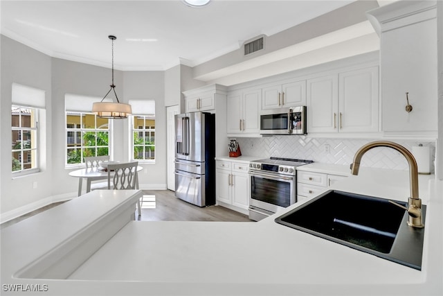 kitchen featuring decorative backsplash, visible vents, appliances with stainless steel finishes, a sink, and light wood-style flooring