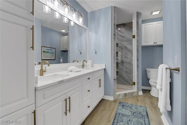 full bathroom with toilet, a shower stall, a sink, and wood finished floors