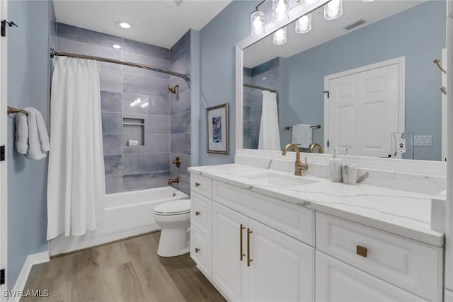 bathroom featuring visible vents, wood finished floors, vanity, toilet, and shower / bathtub combination with curtain