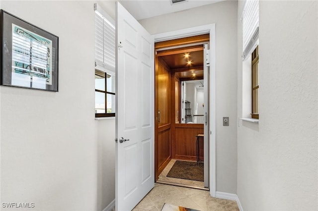 hallway featuring light tile patterned floors and baseboards