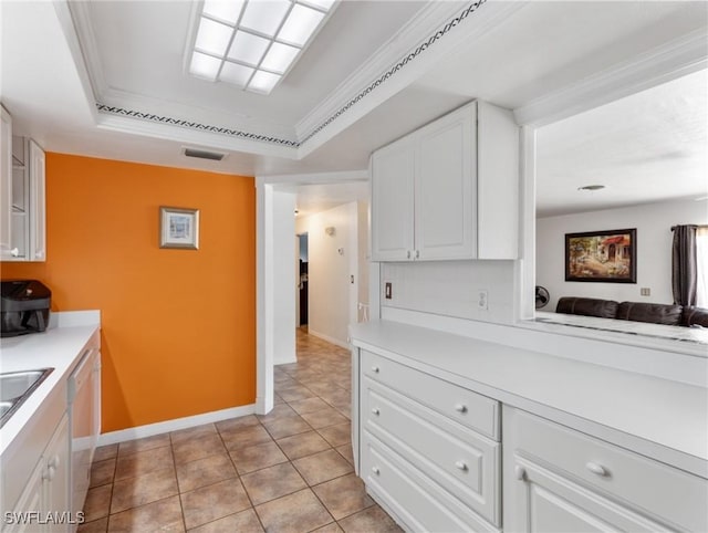 kitchen featuring baseboards, light tile patterned flooring, white cabinetry, a raised ceiling, and light countertops