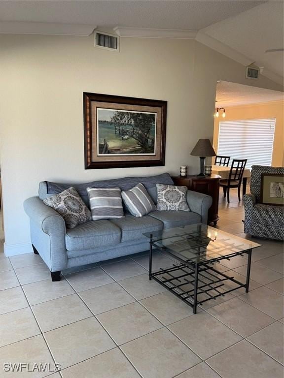 living area featuring vaulted ceiling, light tile patterned flooring, and visible vents