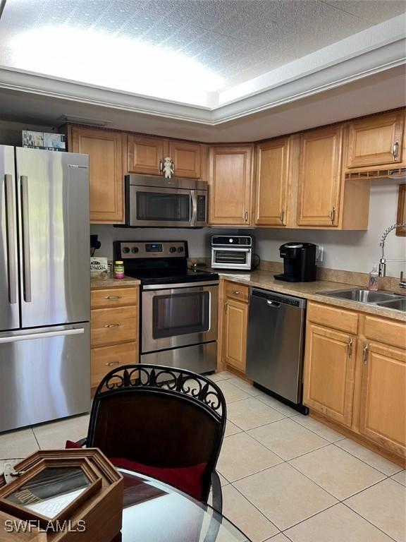 kitchen featuring a sink, appliances with stainless steel finishes, light tile patterned flooring, and light countertops