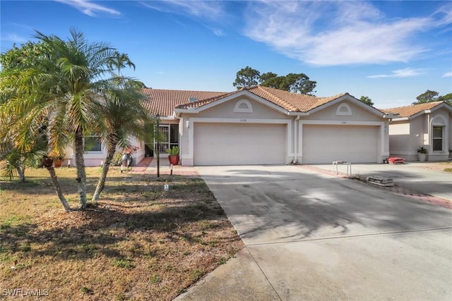 view of front of home with a tile roof, an attached garage, stucco siding, and driveway