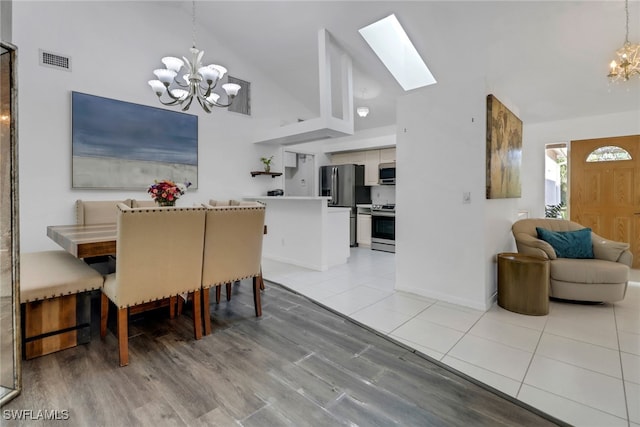 dining area with a skylight, light tile patterned flooring, high vaulted ceiling, visible vents, and an inviting chandelier