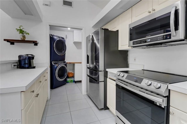 kitchen with light tile patterned floors, visible vents, stacked washing maching and dryer, light countertops, and appliances with stainless steel finishes