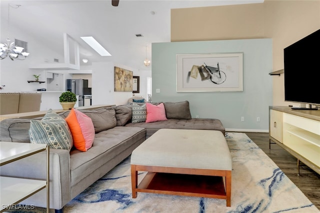 living area featuring a skylight, wood finished floors, high vaulted ceiling, visible vents, and an inviting chandelier