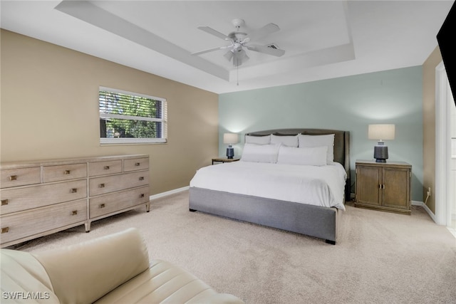 bedroom with light carpet, a raised ceiling, baseboards, and ceiling fan