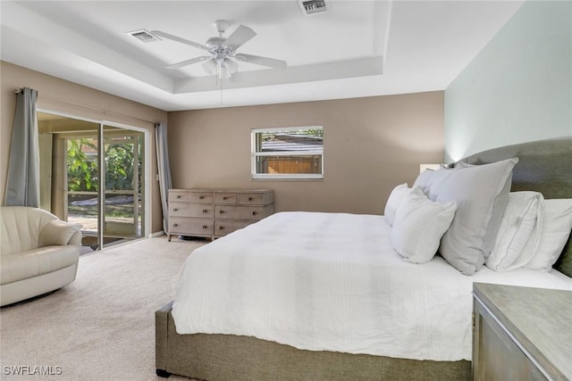 carpeted bedroom with a tray ceiling, ceiling fan, visible vents, and access to exterior